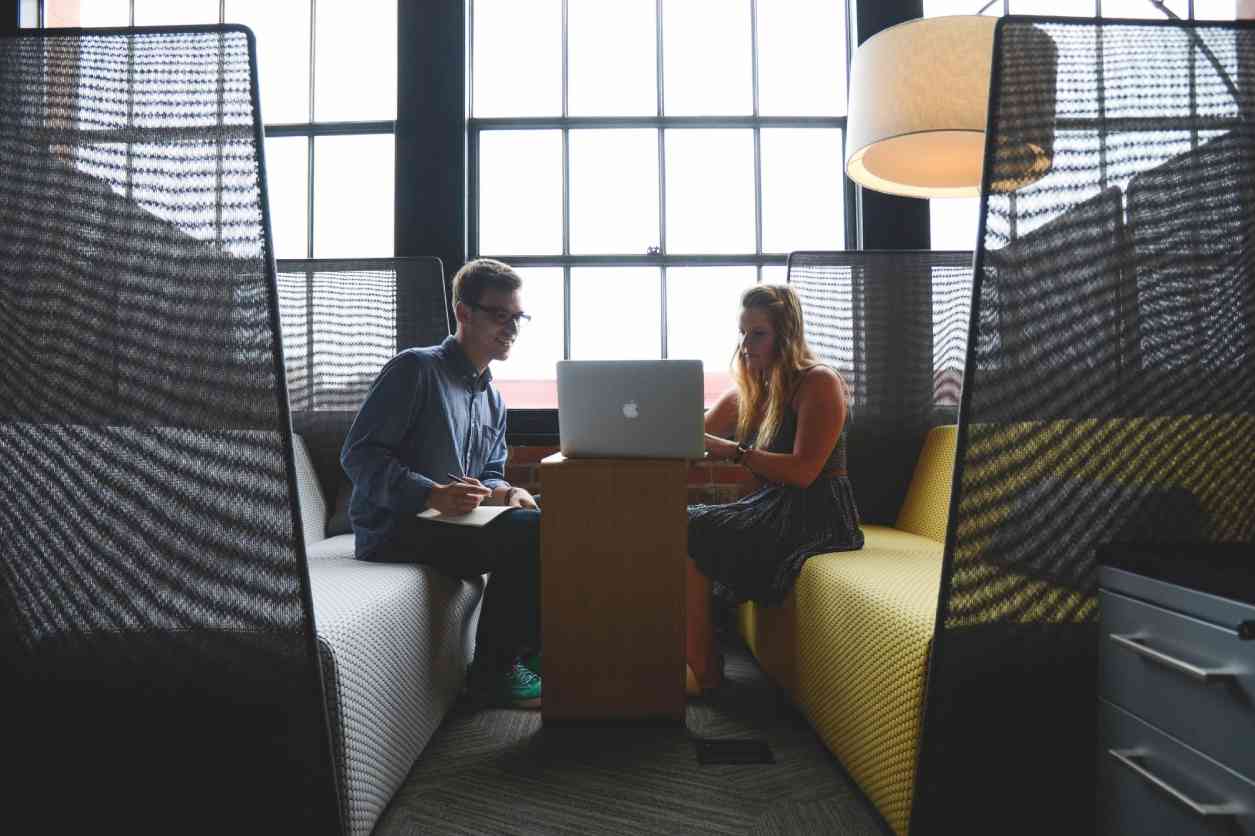 Two people sitting on a couch with laptops